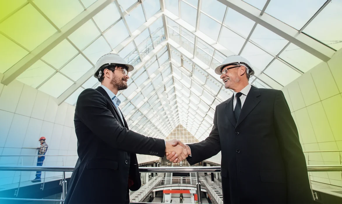 two-cheerful-businessman-handshaking-helmet-new-building copy